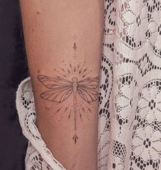 a woman's arm with a tattoo on it and a dragonfly sitting on top of the arm