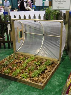 a wooden box filled with plants on top of a green carpeted floor next to a fence