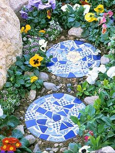 two blue and white mosaic stepping stones surrounded by flowers