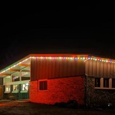 a red brick building with christmas lights on it's roof and windows at night