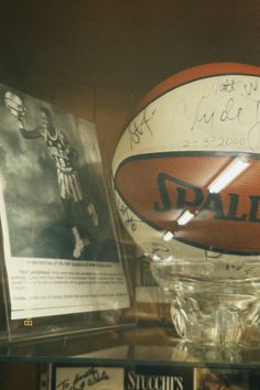 an autographed basketball is on display in a glass case with other memorabilia behind it