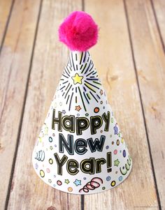 a party hat with the words happy new year written on it and a pink pom - pom