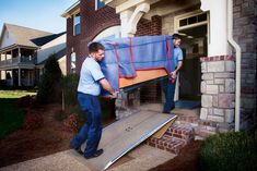 two men unloading furniture from the back of a house