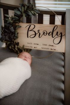 a baby is laying in a crib next to a wooden sign