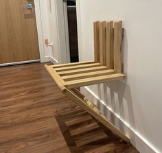 a wooden bench sitting on top of a hard wood floor next to a white wall