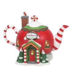 a red and green teapot shaped like a house with candy canes on the roof