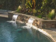 an outdoor swimming pool with waterfall in the middle