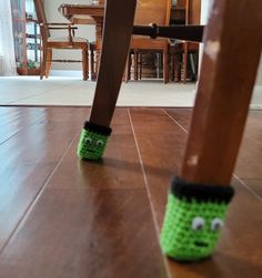 a pair of green slippers sitting on top of a wooden floor next to a dining room table