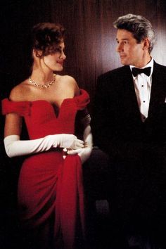 a man in a tuxedo standing next to a woman in a red dress