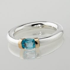 This delightfully hand crafted Sterling silver tension ring makes the ideal choice as a birthstone gift with a mediterranean sea Blue Topaz representing those born in November. The gemstone has a solid gold detail on each shoulder, with the contrasting precious metals enhancing beautifully with the light bright blue of the topaz gemstone. Tension held stones allow the light to reflect the colours without interference from the metalwork. We have been hand making these rings for the last 25 years, Luxury Anniversary Topaz Ring With Bezel Setting, Modern Topaz Birthstone Ring As Gift, Modern Topaz Ring As Birthstone Gift, Blue Topaz Tension Setting Ring Gift, Blue Topaz Rings With Tension Setting For Gift, Topaz Ring With Tension Setting Gift, Gift Topaz Ring With Tension Setting, Tension Ring, Sterling Silver Jewelry Rings