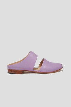 The mule is ZX’s perennial flat, inspired by traditional babouche slippers. With its sleek cut-out upper and almond shaped toe, this style makes feeling comfortable and pulled-together an easy task for days filled with lots of activity. This pair is crafted from vibrant lilac kidskin. Style yours with statement pants for a chic party look. Who it’s for: The woman with refined style who likes to go places by foot. Kidskin leather upper and undyed vegetable-tanned leather lining. Leather sole and stacked heel. Handmade in Argentina. Chic Slides With Rubber Sole For Spring, Chic Spring Slides With Rubber Sole, Chic Slides With Rubber Sole, Modern Clogs With Flat Heel For Spring, Modern Closed Toe Slides For Spring, Chic Slippers With Rubber Sole And Flat Heel, Modern Closed Toe Mules For Spring, Spring Closed Toe Slides With Leather Sole, Spring Flats With Leather Sole And Single Toe Strap