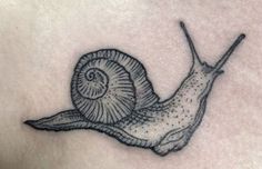 a snail tattoo on the back of a woman's chest, with black ink