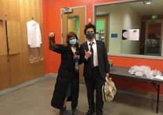 two people wearing masks in an office hallway