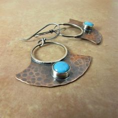 "Hammered copper and bright little blue 6mm Kingman turquoise are a beautiful match for a pair of rustically elegant earrings. The contrast of the sterling silver ring and ear wires against the copper is a lovely example of the charm of mixed metals. The turquoise cabochons are set in fine silver bezels which adds an additional element of contrast. We have oxidized and polished them for a richness that only oxidation can provide and it gives them an earthy appeal. Lightweight and easy to wear in Copper And Turquoise, Silversmith Jewellery, Metalwork Jewelry, Mixed Metal Earrings, Contemporary Earrings, Celebrity Engagement Rings, Kingman Turquoise, Hammered Copper, Everyday Earrings