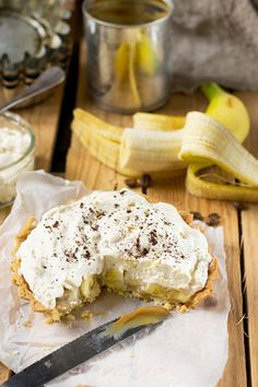 a banana cream pie on a piece of wax paper with a knife next to it