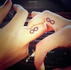 two people holding hands with tattoos on their fingers and the other hand is pointing at them