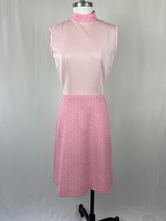 "An absolutely darling pastel pink polyester dress.  Bodice is plain light pink; skirt is a darker geometric texturized pink. Mock neck, sleeveless, back zipper, darts in bodice. Fabric is medium weight and slightly stretchy.  So cute! Shoulder width: 16-1/2\" Bust: 39\" Waist: 28\" Back neck to bottom hem of dress: 40\" Circumference of armholes: 16\" We can't help but think this belongs on Laurie Partridge! We always want you to be pleased with your purchase! We have included detailed measurem Pink A-line Sleeveless Dress, Fitted Pink Lined Sleeveless Dress, Pink Retro Dress For Work, Pink Fitted A-line Sleeveless Dress, Vintage Pink Dress For Work, Retro Pink Dress For Work, Fitted Pink Sleeveless Dress For Work, Pink A-line Sleeveless Lined Dress, Pink Mod Dress For Spring