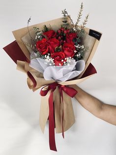 a bouquet of red roses wrapped in brown paper