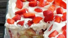 a close up of a cake with strawberries on top and whipped cream frosting