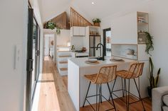 an open concept kitchen and living room with wood flooring, white countertops and bar stools