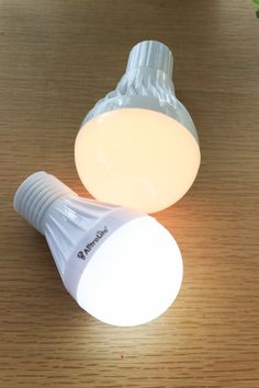 two light bulbs sitting on top of a wooden table