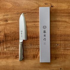 a knife sitting on top of a wooden table next to a box with chinese writing