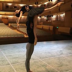 two people standing on one leg in front of an auditorium