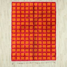 an orange and red rug on a wooden floor