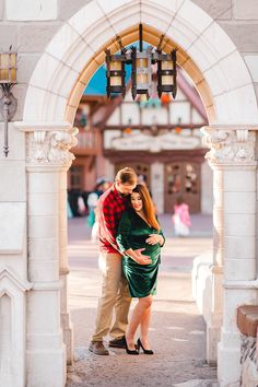 a man and woman standing under an archway with their arms around each other as they cuddle