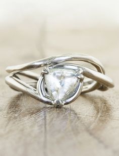 a white diamond ring sitting on top of a wooden table