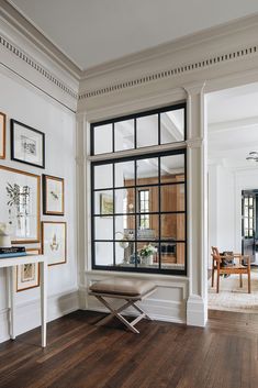 a living room filled with furniture and framed pictures on the wall next to a window