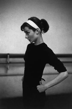 black and white photograph of a woman with her hands on her hips wearing a headband