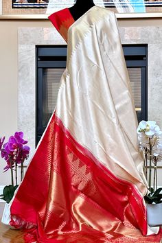 This stunning kanjivaram saree is handwoven in tussar white woven in ettu kol technique. The borders have an ettu kol temple reku woven in gold zari. The grand pallu in vermilion red color features an ettu kol band in gold zari bordering with peacocks and traditional motifs. Approximate Length 6.5 mtrs (inclusive of blouse length) Approximate Height - 48 - 52" Approximate weight - 1.7 lbs Saree comes with fall, picot and tassels done when applicable. Blouse piece is cut. Kindly Note : The colors you see on your device may vary due to the color reproduction, brightness and resolution of individual devices. If you'd like more clarity before your purchase, please contact our support team. Wedding Raw Silk Pre-draped Saree With Border, Pre-draped Raw Silk Saree With Border For Festivals, White Slub Silk Pre-draped Saree, White Slub Silk Pre-draped Saree For Festive Occasions, Traditional Slub Silk Wear In Cream, Cream Slub Silk Traditional Wear For Festivals, Cream Slub Silk Traditional Wear, Traditional Cream Slub Silk Wear, White Banarasi Silk Dupatta With Border