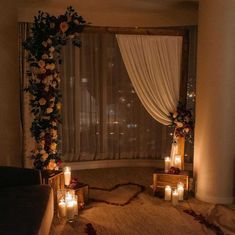 candles are lit in front of a window decorated with roses and greenery for a wedding ceremony