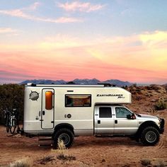 a truck with a camper attached to it parked in the desert