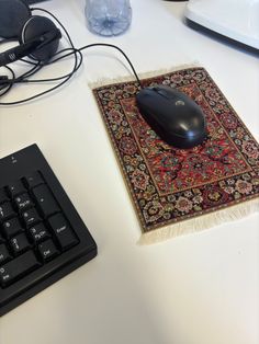 a computer mouse sitting on top of a rug next to a keyboard and mouse pad