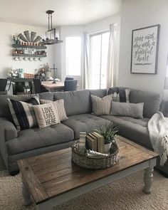 a living room with gray couches and pillows on the coffee table in front of it