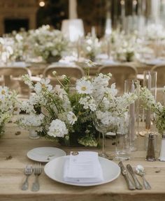 the table is set with white flowers and silverware