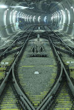 the inside of a train station with many tracks and lights on it's sides