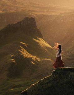 a woman standing on top of a hill with her hair blowing in the wind,