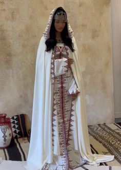 a doll dressed in white and red is standing next to a rug on the floor