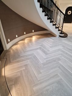 an empty room with white and grey herringbone flooring next to a spiral staircase