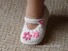 a small child's foot wearing crocheted shoes with pink flowers on them