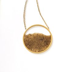 Handmade gold-colored necklace with sand from the beaches of Barcelona. The sand is attached to a  30mm gold-colored circle, giving it a floating appearance. The  gold necklace is 18 inches long and is made of stainless steel. Gold Round Beach Jewelry, Minimalist Gold Necklaces For The Beach, Gold Minimalist Necklace For Beach, Gold Round Jewelry For Beach, Gold Round Jewelry For The Beach, Minimalist Gold Necklace For Beach, Gold Round Pendant Necklace For Beach, Gold Round Pendant Jewelry For The Beach, Sand Jewelry