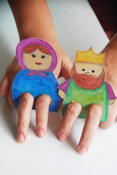 two children's hands holding small paper dolls