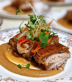 a plate topped with meat covered in sauce and garnished with veggies