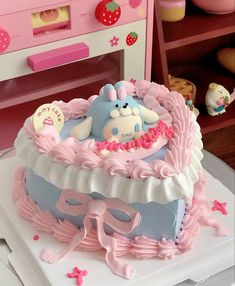 a pink and blue cake sitting on top of a white table next to a toy oven