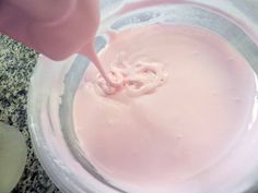 someone is mixing pink liquid in a glass bowl