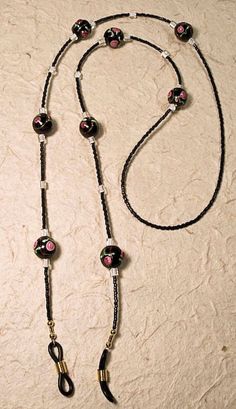 This eyeglass leash features black glass lamp work beads with tiny roses, black Japanese seed beads and white glass Japanese cube beads for accent.  The ends are black rubber with either gold or silver tone spirals.  Average length is about 27-28 inches, but can be longer or shorter, if requested. Black Glass Round Bead Jewelry, Black Glass Round Beads Jewelry, Handmade Black Glass Beads, Handmade Glass Beads In Black, Black Glass Beaded Jewelry, Adjustable Black Wire Wrapped Beaded Necklaces, Black Glass Beaded Necklaces With Beaded Chain, Adjustable Black Wire Wrapped Beaded Necklace, Black Glass Beaded Necklace With Beaded Chain