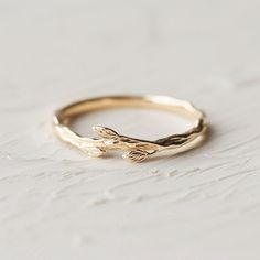 a gold ring with two leaves on it, sitting on a white tableclothed surface